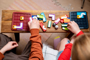Two children playing with Genius Connection puzzle game on wooden table