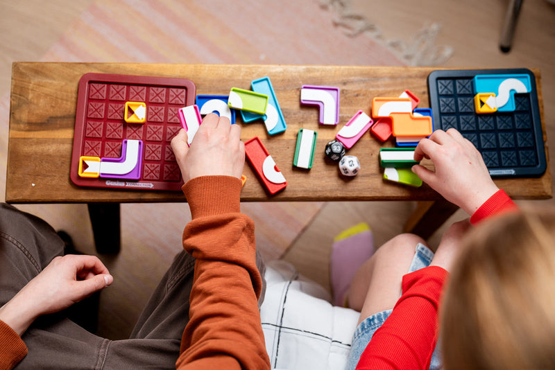 Two children playing with Genius Connection puzzle game on wooden table