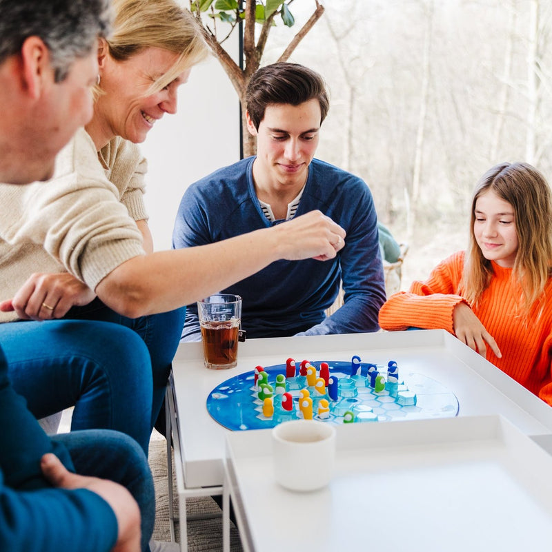 Family playing Penguins Huddle Up board game together at white table