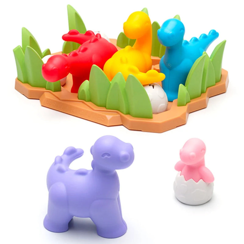 The game board and pieces on a white background, featuring a base with colorful dinosaur figures, grass, and a white egg, plus three loose dinosaur figures in purple, yellow, and blue, and a small pink dinosaur in an egg.