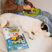 Dog laying next to child playing the Smart Dog puzzle game on a couch.