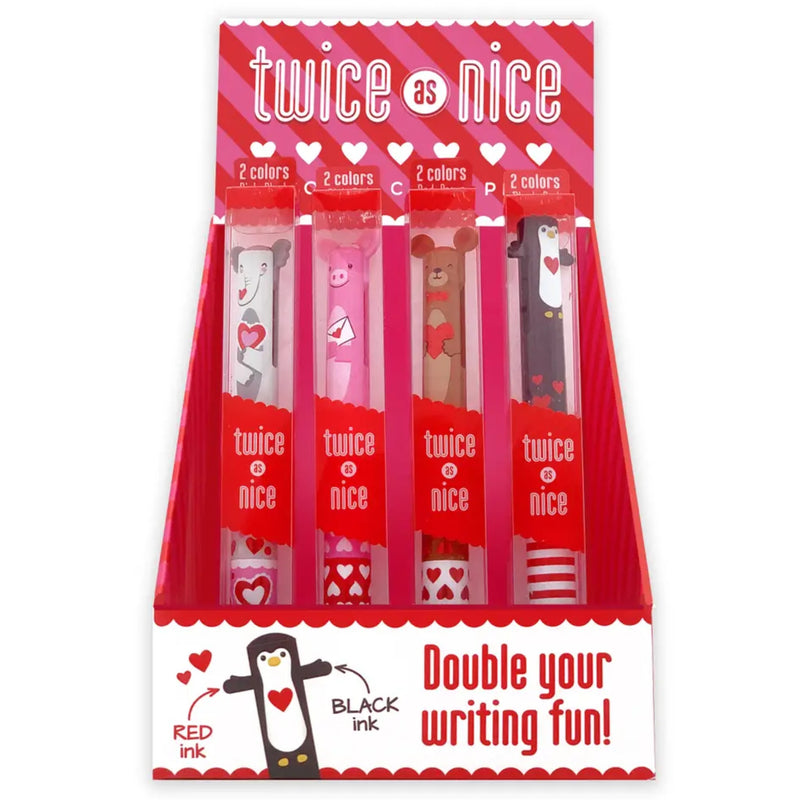 Twice as Nice double writing ink set in a red and white cardboard valentine retail display box. The display contains four tubes of pens with different animal illustrations (dog, cat, bear, penguin) and red/black heart patterns, with text reading 'twice as nice' and 'Double your writing fun!'.