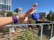 Person demonstrating blue Waboba Moon bounce ball with wrist strap outdoors