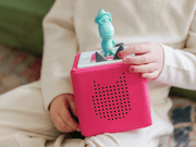 Child holding pink Toniebox audio player with teal character figure on top