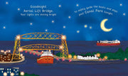 A whimsical illustrated night scene with a yellow aerial lift bridge over water, glowing ship lights, boats, stars, a crescent moon, and decorative text reading 'Goodnight Aerial Lift Bridge' and 'to safely guide the boats and ships past Canal Park tonight.' The artwork is centered on a white page background.