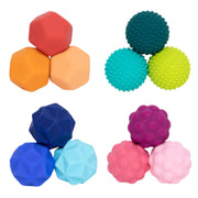 Six colorful textured Speks Odds arranged in separate groups on a plain white background. The left group contains smooth geometric balls in red, orange, peach, dark blue, light blue, and royal blue.