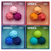 Four packaged SPEKS. soft silicone budget magnets and target magnets arranged in a 2x2 grid, each box showing three colorful spherical magnets inside a translucent colored case.