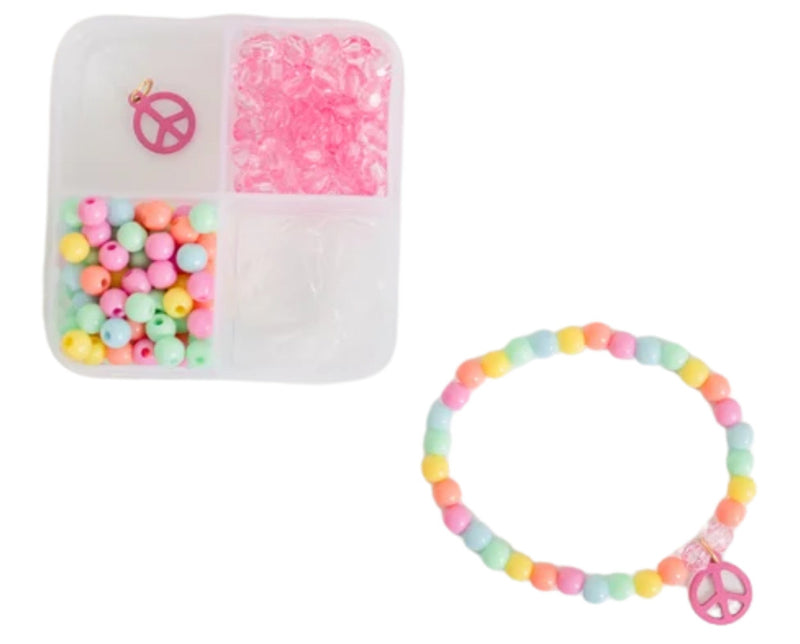 A beaded bracelet set shown on a white background, including a completed pastel multicolor beaded bracelet with a pink peace sign charm, and a clear compartment organizer filled with pink rhinestones and pastel beads.