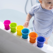 Toddler playing with Sucktion Kupz on the side of the bathtub.