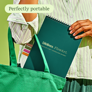 Person holding green FlowArt Woodland Whimsy notebook in tote bag