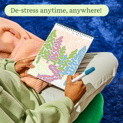 Person using FlowArt coloring book with intricate patterns while relaxing outdoors