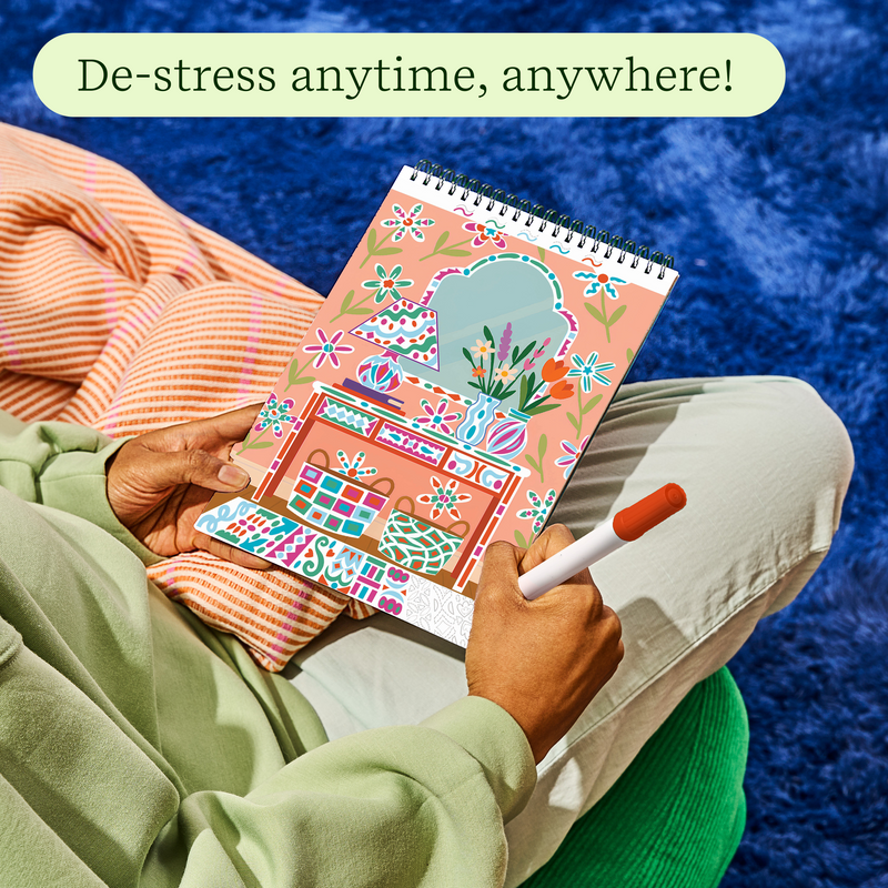 Person using FlowArt coloring book with colorful designs while relaxing