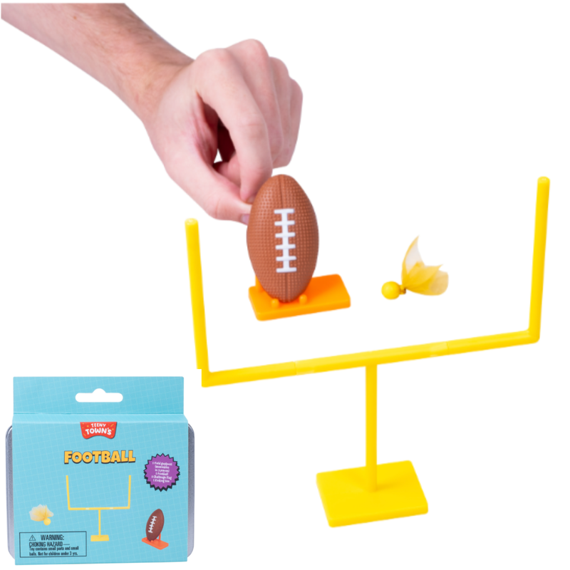 Toy football set with a hand placing a toy football into a goal post, on a white background.