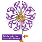 A colorful mechanical flower wind spinner toy with purple petals, an orange and white center, and a green stem on a white background, featuring a purple text box at the bottom left that reads 'Build a spinning mechanical flower!'.