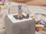 Tonie figurine on speaker with children's books in background