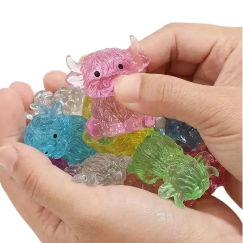 A pair of hands holding a pile of translucent, highland cows in multiple colors, including pink, blue, green, yellow, and clear.