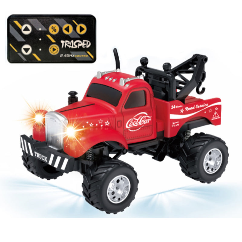 A red mini remote-controlled monster truck with black off-road tires, a black tow bar, and bright headlights, shown on a white background with a black remote control in the top left corner.