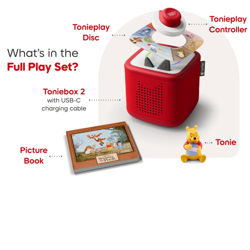 Tonnebox 2 full play set shown on a light gray background with callout labels pointing to included items: a red Tonniebox 2 speaker, red and white Tonieplay controller and disc, a picture book, and a small yellow Tonie figure.