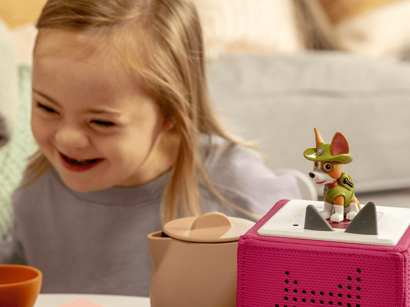 Child playing with Paw Patrol Tracker Tonie figure on pink Toniebox speaker