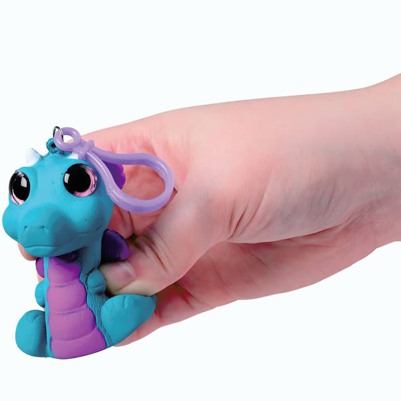 Blue and purple squishy dragon toy with glitter eyes being held in hand