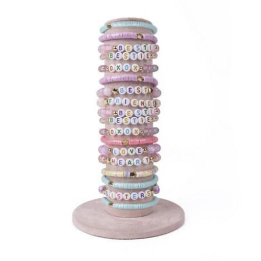 Stack of pastel colored beaded bracelets with letter beads on wooden stand
