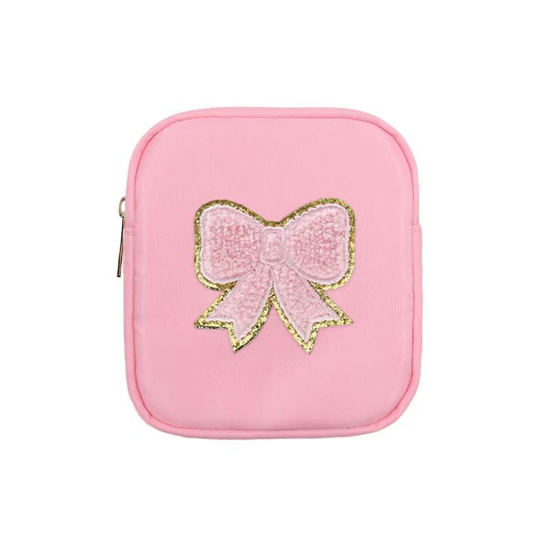 Pink square bag with embroidered bow design featuring gold outline and sequined details