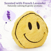 A yellow plush smiley face pillow with black embroidered eyes and a curved smile, shown on a white background with lavender-themed decorative graphics and text reading 'Scented with French Lavender Naturally calming & gently aromatic.'.