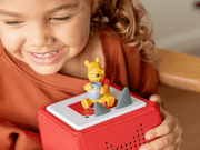 Child holding red Toniebox with Winnie the Pooh Tonie figure on top