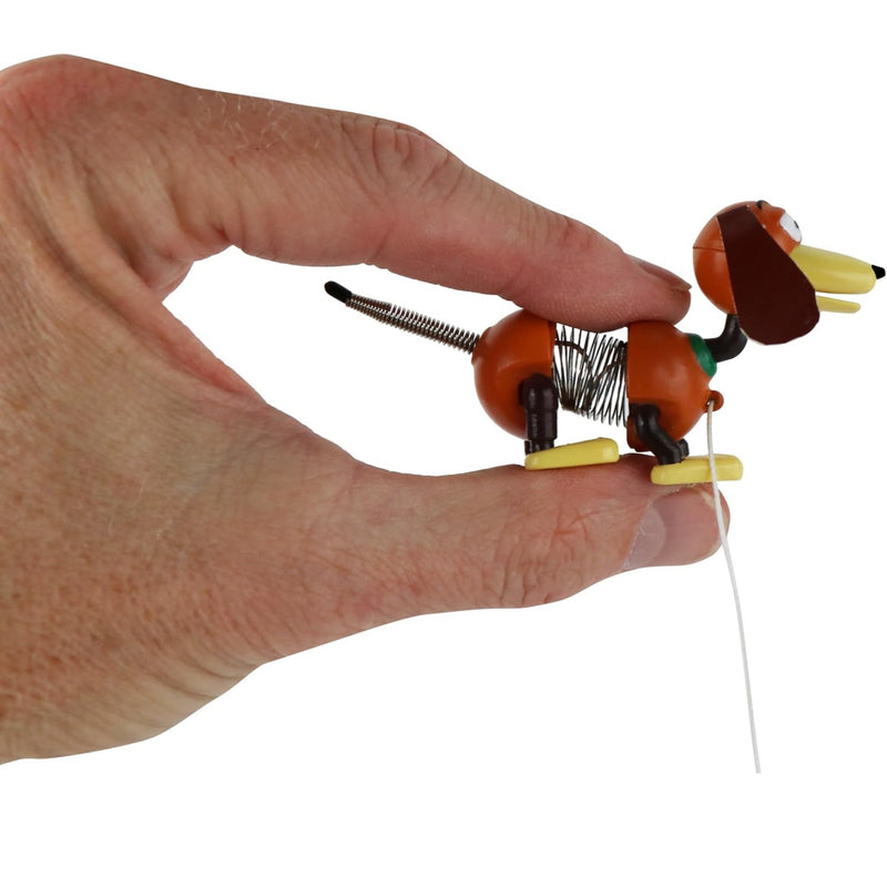 A hand holding a small spring-loaded dachshund toy against a plain white background.