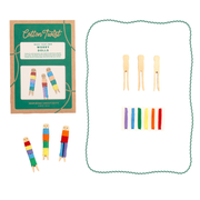 Contents of Cotton Twist Make Your Own Worry Dolls craft kit with thread, clothes pins, ackaging, and completed dolls.