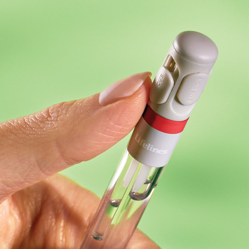 Hand holding white pen diffuser device against green background demonstrating usage