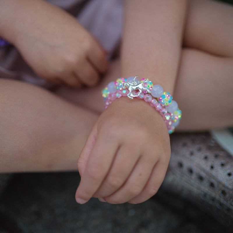 Child wearing colorful beaded bracelet with silver unicorn charm on wrist