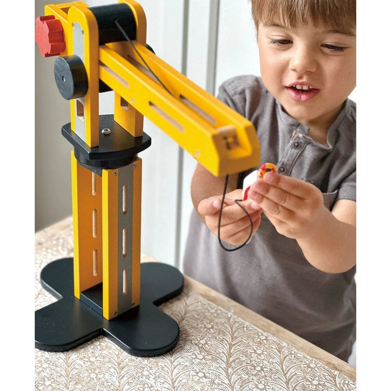 Child playing with yellow wooden crane toy by Mentari