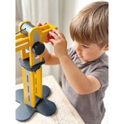 Child playing with yellow Mentari wooden crane toy in bright indoor setting