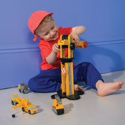 Child playing with yellow Mentari toy crane and construction vehicles in studio setting