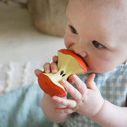 Baby holding and chewing on Pepa the Apple teething toy by Oli & Carol
