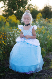 Young girl wearing light blue Cinderella princess gown costume in garden setting