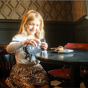 Young girl wearing sparkly sequined skirt at table in restaurant setting