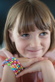 Young girl wearing colorful beaded bracelet with rainbow gumball-style beads