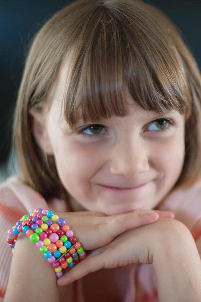 Young girl wearing colorful beaded bracelet with rainbow gumball-style beads
