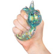 Hand squeezing a clear glitter-filled unicorn squishy stress toy with teal sparkles