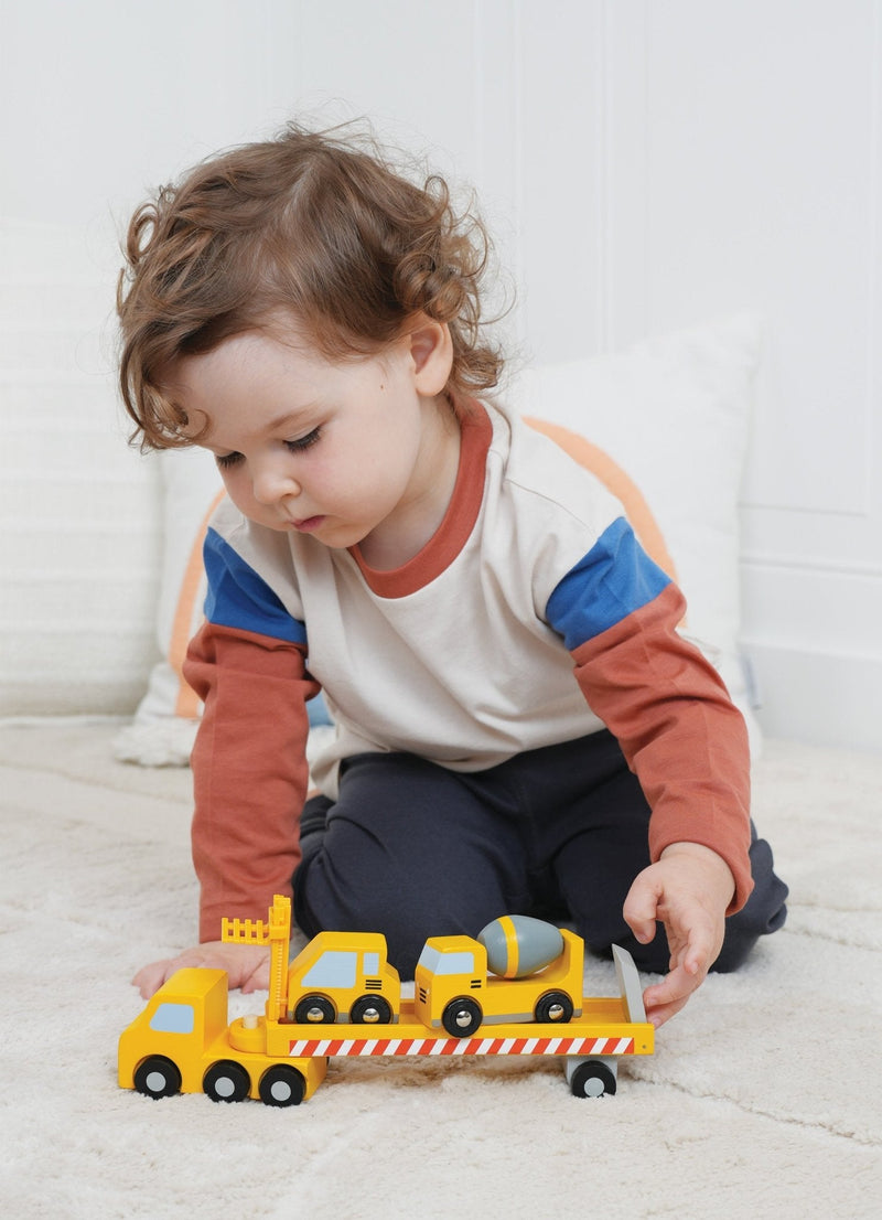 Child playing with yellow Mentari Construction Transporter truck carrying construction vehicles