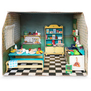Cardboard dollhouse kitchen room with miniature furniture and accessories on checkered floor