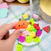 Hand holding kawaii orange mochi squishy with assorted fruit mochi squishies on plate