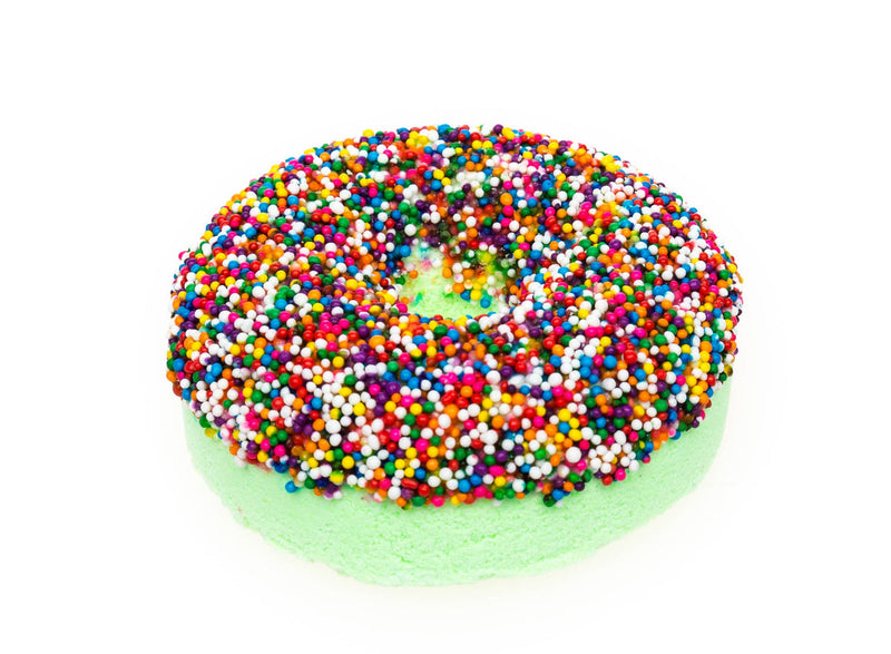 Green donut-shaped bath bomb covered in colorful rainbow sprinkles on white background