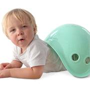 Young child playing with mint green Bilibo shell toy on white background