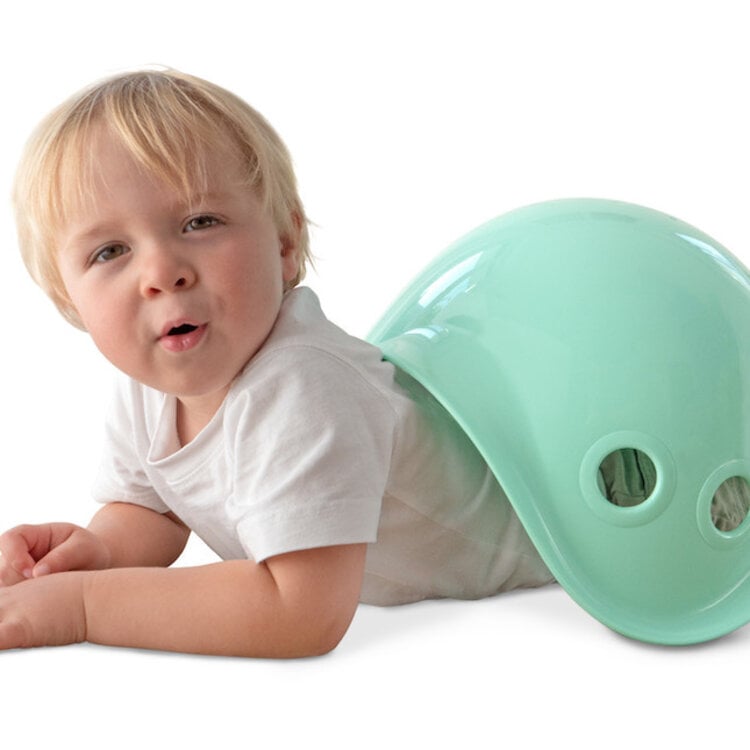 Young child playing with mint green Bilibo shell toy on white background