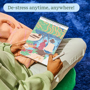 Person relaxing while using FlowArt dot painting book with colorful design