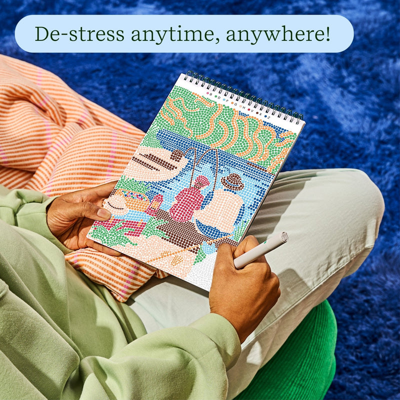Person relaxing while using FlowArt dot painting book with colorful design