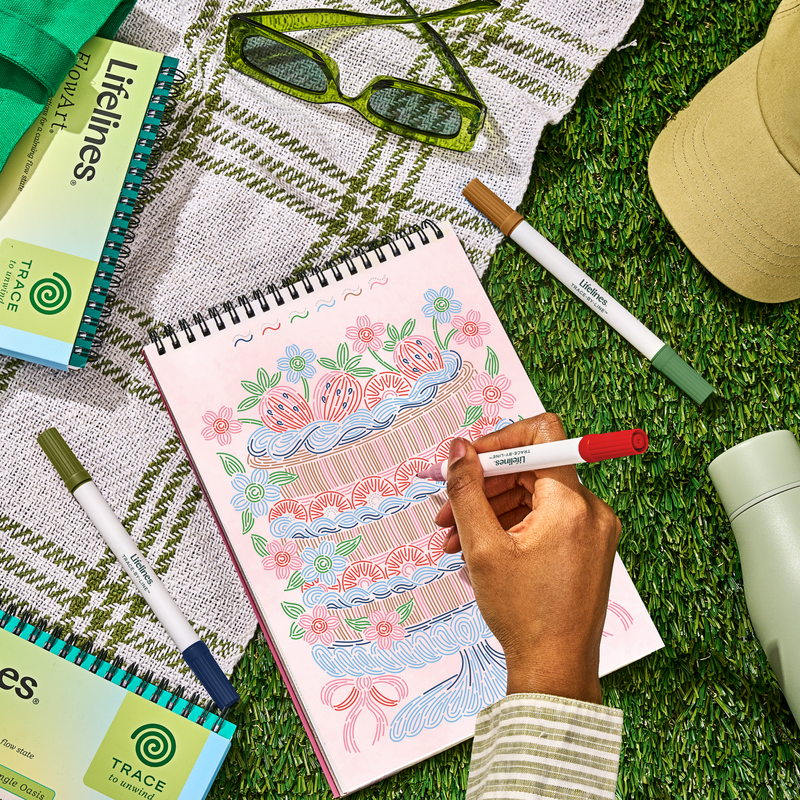 Hand drawing in Lifelines FlowArt Trace-by-Line Brunch in Bloom sketchbook outdoors on grass